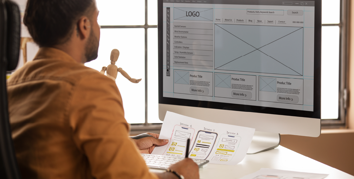 Web Application Development process showing a designer planning website wireframes and UI layout on paper and computer screen.